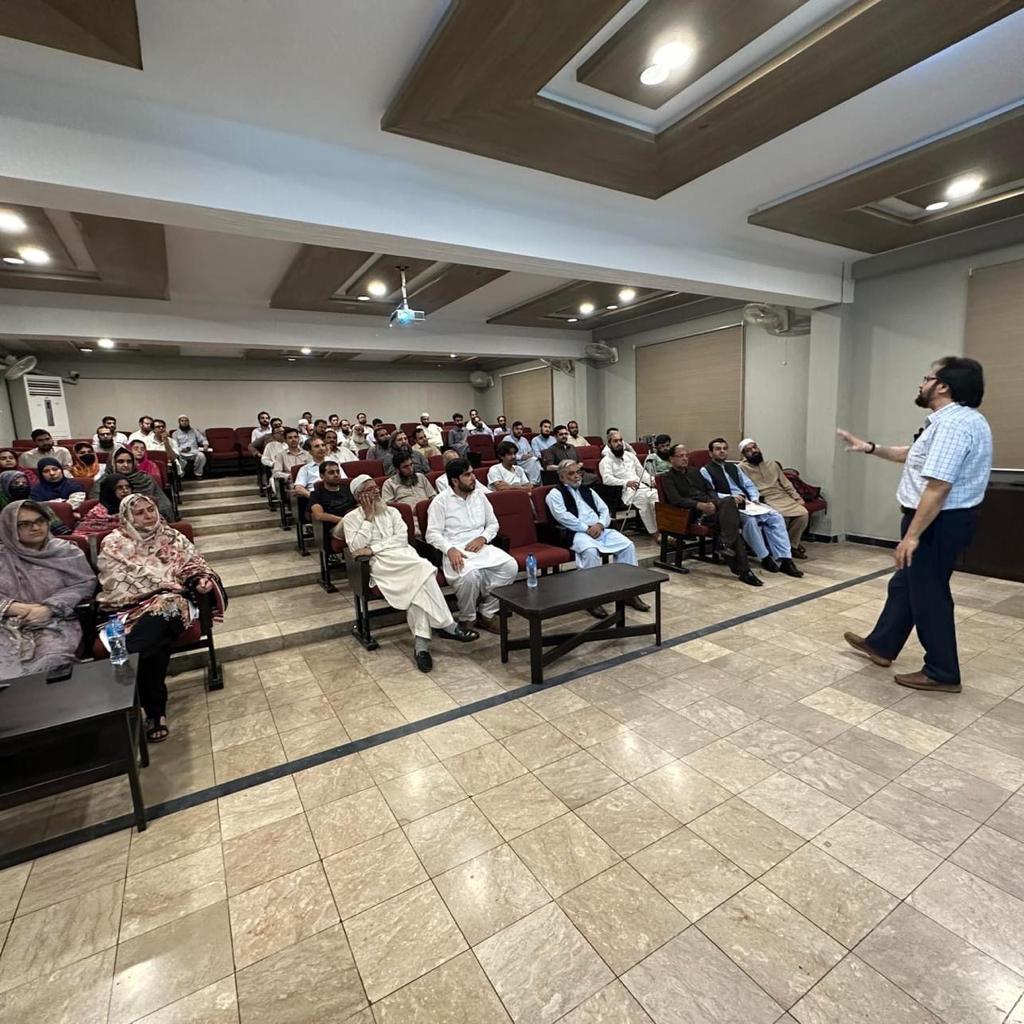 Prof. Dr. Abdul Baseer Qazi speaking to a full hall